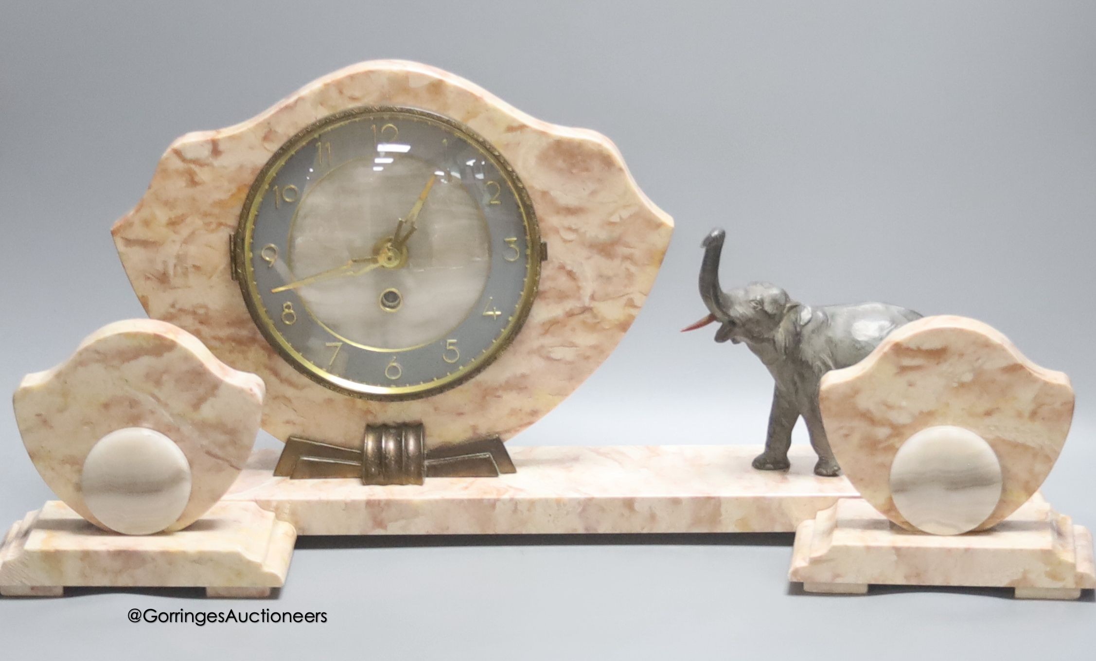 An Art Deco style pink marble 'elephant' clock garniture, length of middle piece 50cm